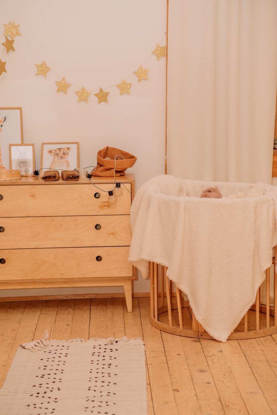 Eine Holzkommode und ein Kinderbett in einem gemütlichen Babyzimmer.